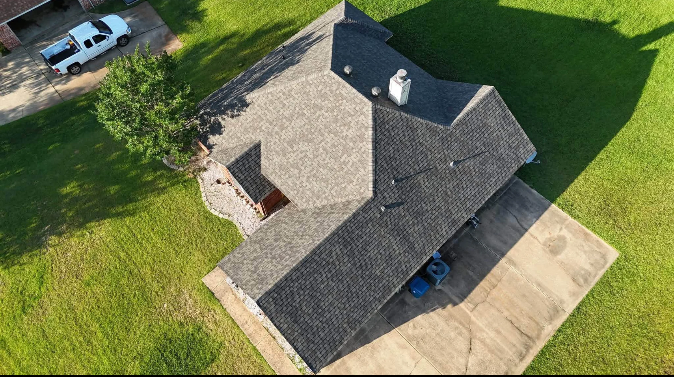 Charcoal gray architectural shingles on multi-pitched residential roof with ridge vents