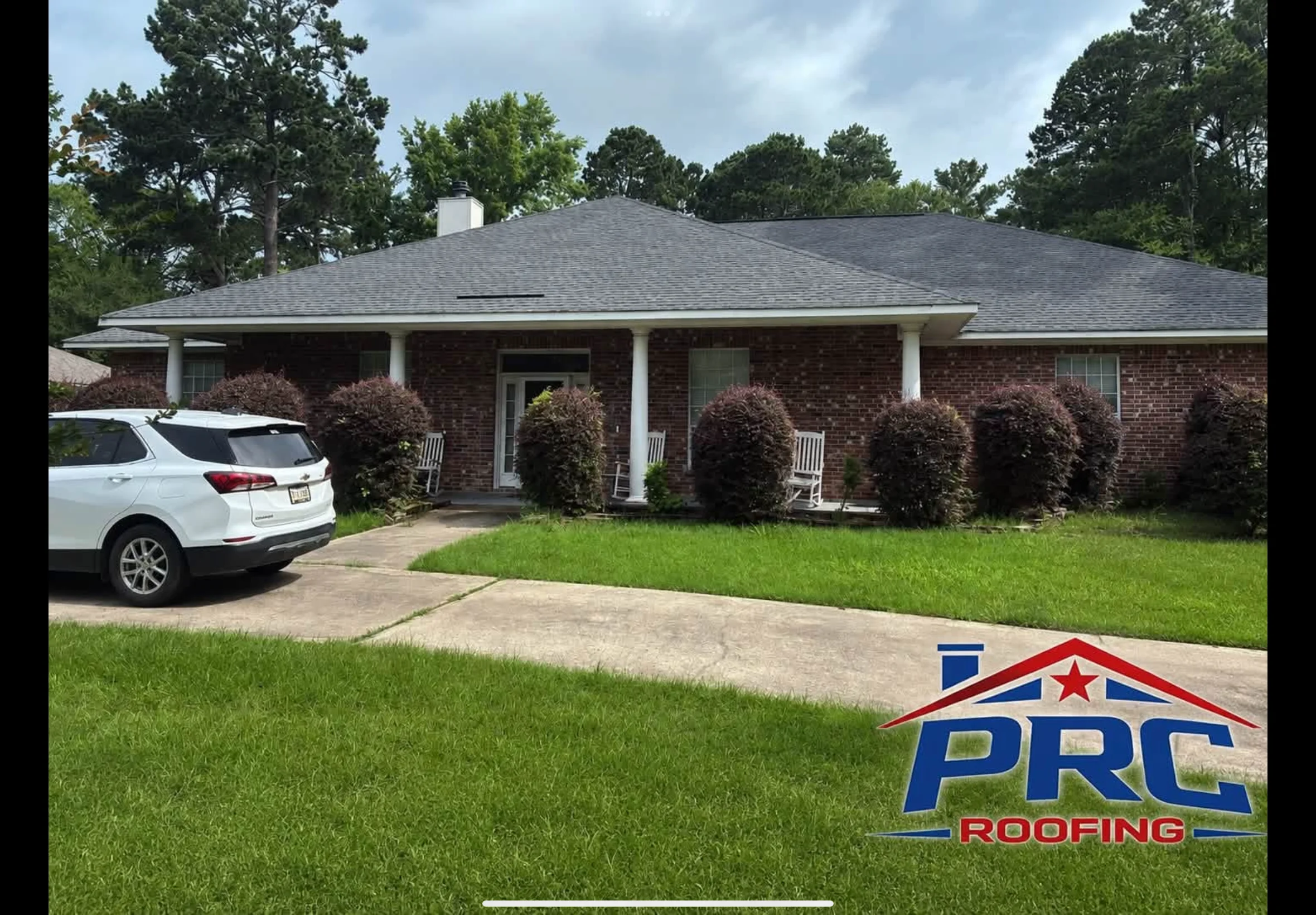 Charcoal gray architectural shingle roof on brick home with white columns and front porch