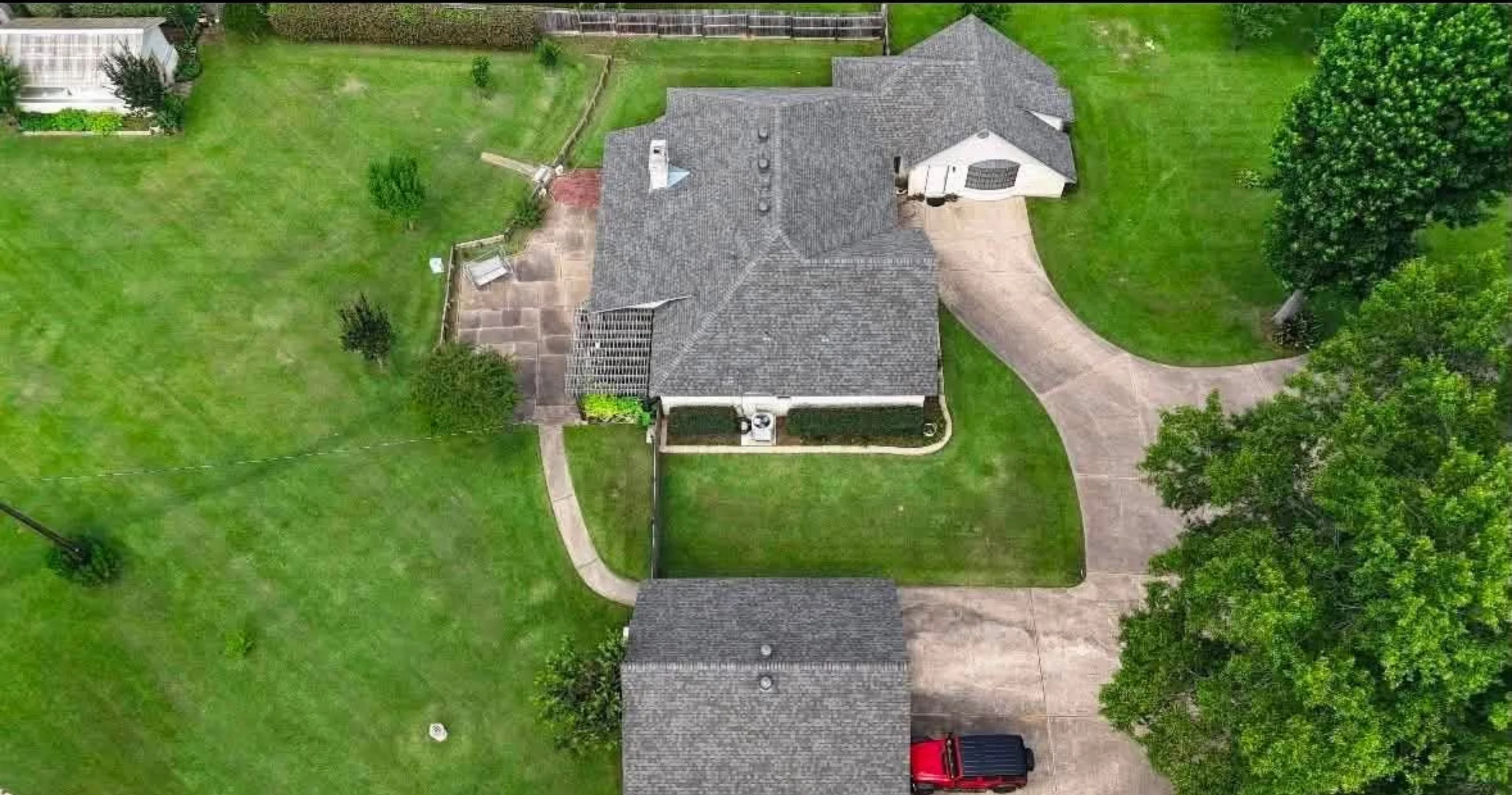 Aerial view of residential roof with gray dimensional shingles, white trim, and attached garage